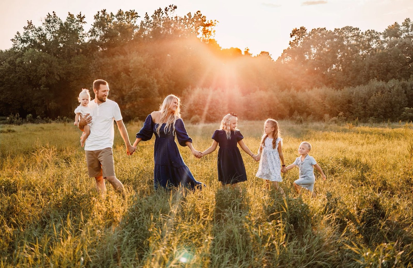 A family holding hands in a sunlit field